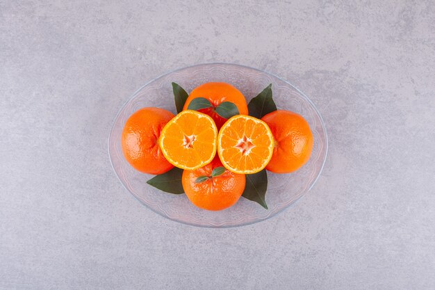 Frutti interi di arancia con mandarino affettato posto su una superficie di pietra.