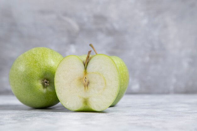Frutti interi e affettati di mela verde matura fresca posizionati su uno sfondo di marmo. Foto di alta qualità