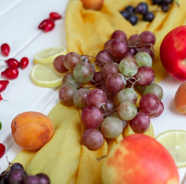 Frutti misti su un nastro giallo su una tavola bianca.