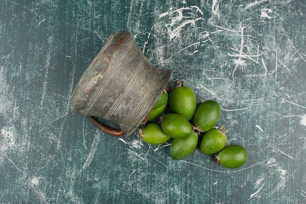 Frutti verdi di feijoa che cadono dal vaso sulla superficie di marmo.