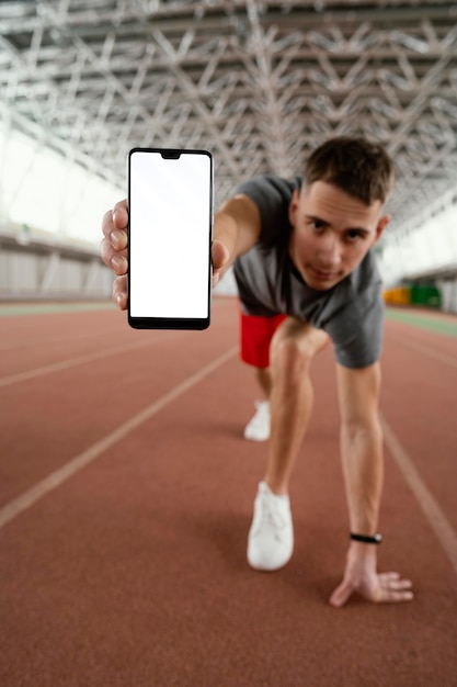 Full shot atleta tenendo lo smartphone