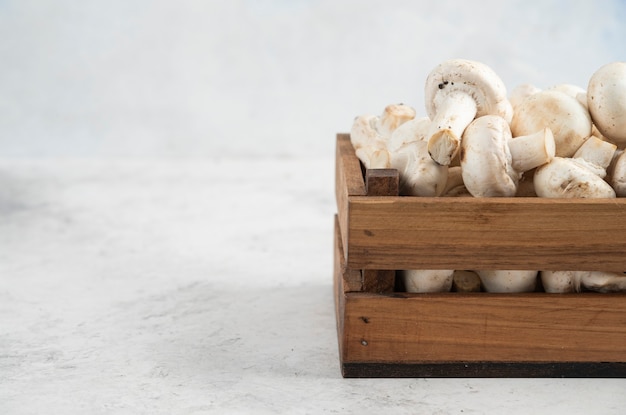 Funghi bianchi all'interno di un vassoio di legno su un tavolo di marmo.