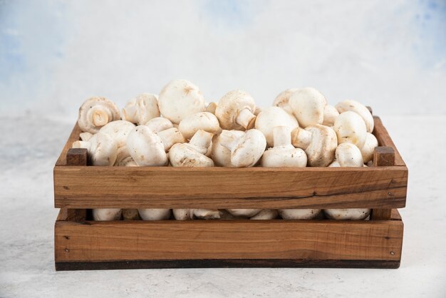 Funghi bianchi all'interno di un vassoio di legno su un tavolo di marmo.