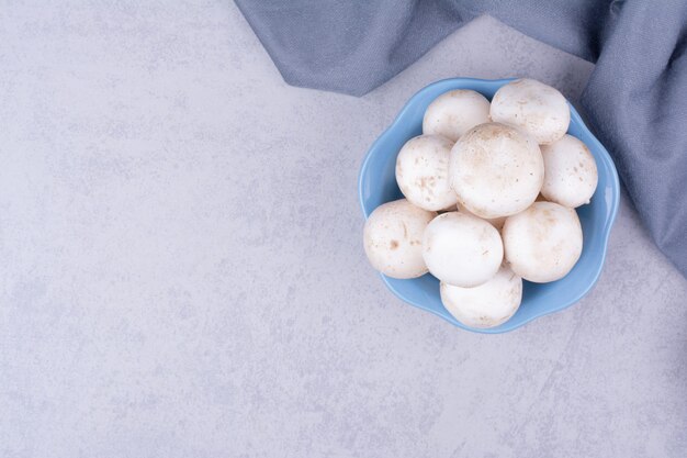 Funghi in una tazza blu su superficie grigia