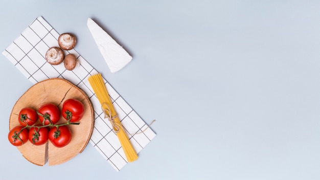 Fungo; pomodori rossi; pasta di formaggio e spaghetti con tovagliolo su sfondo grigio