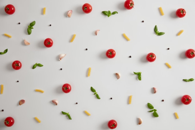 Fusilli crudi intorno a pomodori e spezie diverse per preparare un pasto delizioso. Cucina italiana classica tradizionale. Vista dall'alto di ingredienti freschi per cucinare la pasta. Cibo nutriente