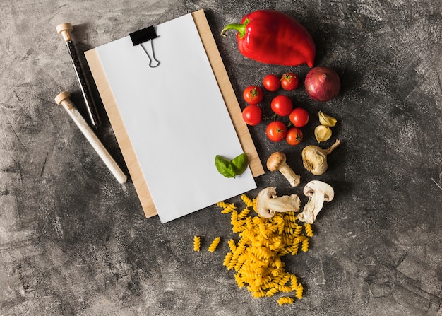 Fusilli crudo con ingredienti e carta su appunti su sfondo grunge