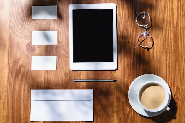 Gadget, caffè, strumenti di lavoro su un tavolo di legno per interni.