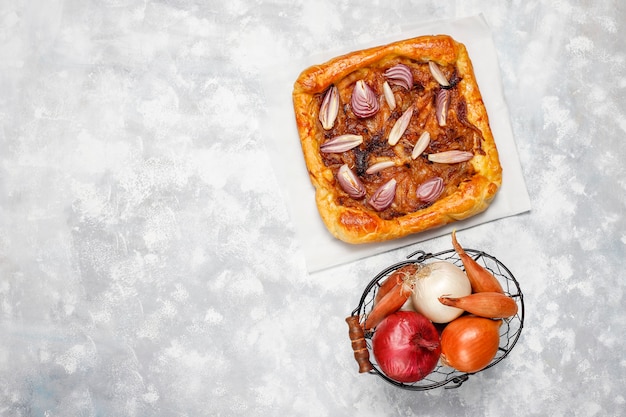 Galette torta di cipolle alla francese con pasta sfoglia e varie cipolle scalogno, cipolle rosse, bianche, gialle, vista dall'alto