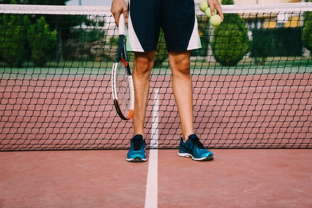 Gambe del giocatore di tennis davanti alla rete