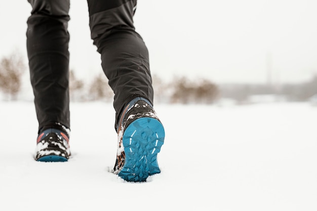 Gambe del primo piano che camminano nella neve