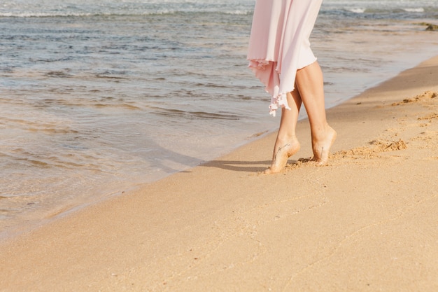 Gambe della donna che camminano sulla sabbia della spiaggia