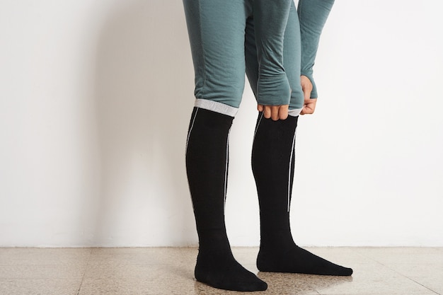 Gambe di atleta maschio in baselayer invernale e calze termiche lunghe nere