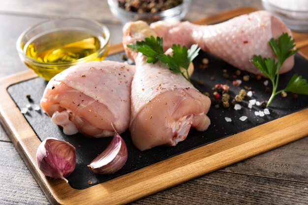 Gambe di carne di pollo cruda sulla tavola di legno