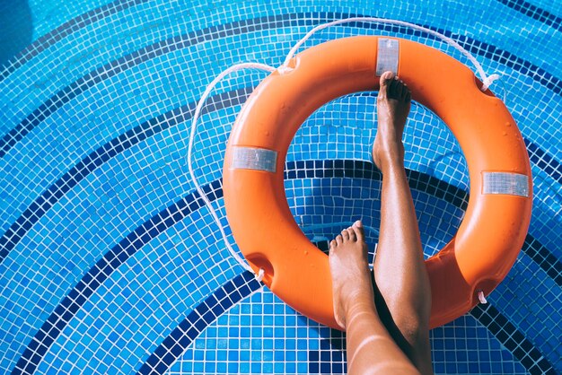 Gambe di donna in una piscina con salvagente