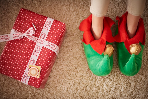 Gambe di elfi accanto al regalo di Natale