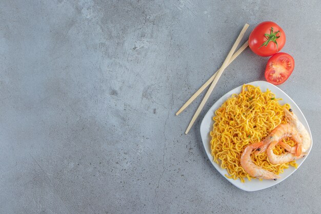 Gamberetti e noodle su un piatto, sullo sfondo di marmo.
