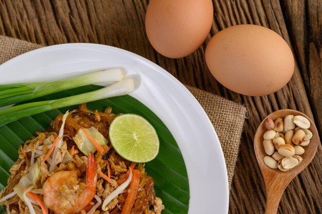 Gamberetto di Padthai in un piatto bianco con calce e le uova sulla tavola di legno.