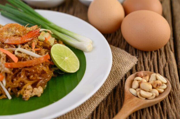 Gamberetto di Padthai in un piatto bianco con calce e le uova sulla tavola di legno.