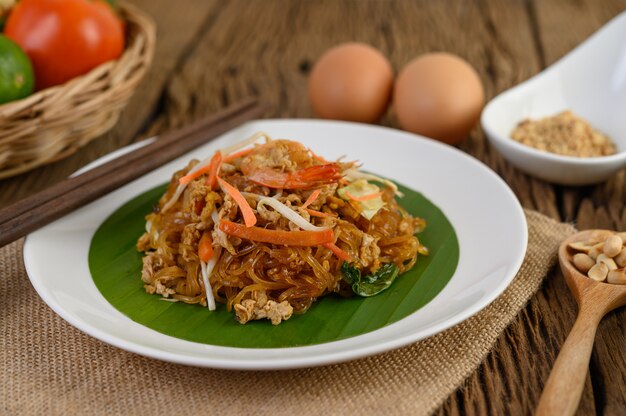 Gamberetto di Padthai in una ciotola nera con le uova, la cipolla di inverno e il condimento sulla tavola di legno.