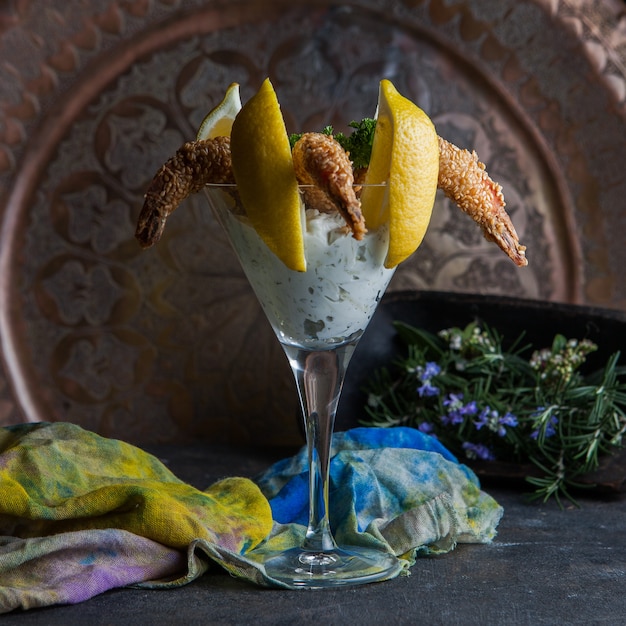 gamberi con semi di sesamo con foglie di limone e rosmarino e straccio in un bicchiere da cocktail