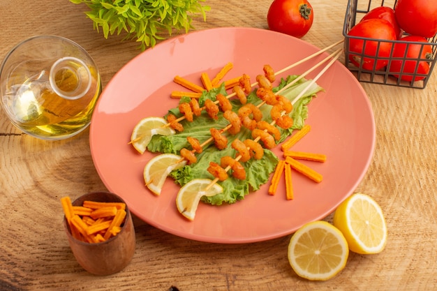 gamberi cotti su bastoncini all'interno del piatto di pesche con fette di limone olio di insalata verde sulla scrivania in legno