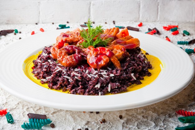 gamberi in pastella con riso rosso e verdure nel piatto bianco