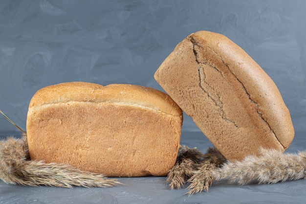 Gambi di erba piuma e pagnotte di pane si raggruppano sul tavolo di marmo.