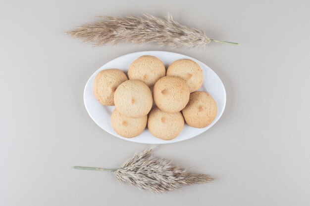 Gambi di Needlegrass accanto a un piatto di biscotti su sfondo di marmo.