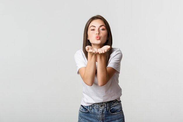 Gara attraente giovane donna che soffia aria bacio alla telecamera flirty.