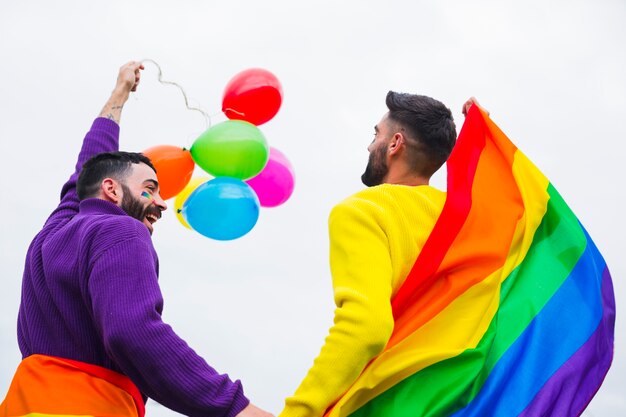Gay con bandiera arcobaleno e palloncini che si godono la sfilata