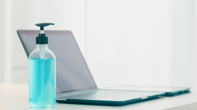 Gel disinfettante per le mani per la protezione da virus corona igiene delle mani con computer portatile. Il distanziamento sociale resta a casa e il tempo di auto-quarantena, lo shopping online, il concetto di coronavirus.