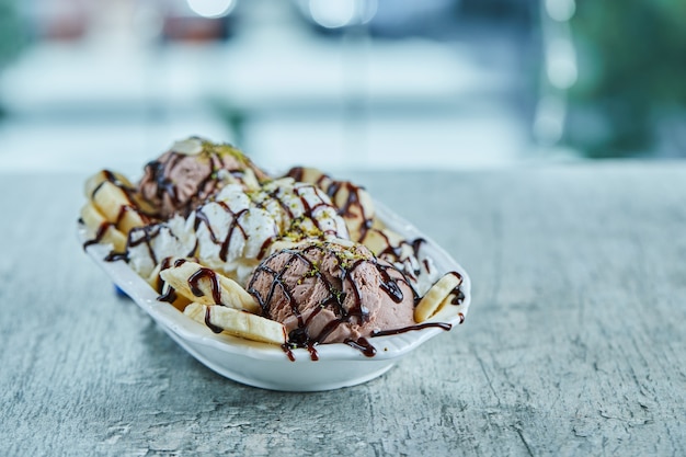 Gelato con banane, cioccolato e spruzza sulla zolla bianca