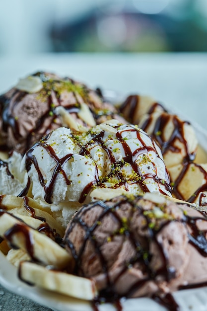 Gelato con banane, cioccolato e spruzza sulla zolla bianca