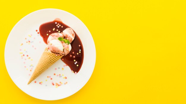 Gelato nel cono di cialda con sciroppo sul piatto