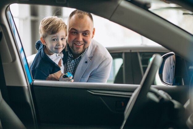 Generi con il figlio che esamina un&#39;automobile in una sala d&#39;esposizione dell&#39;automobile