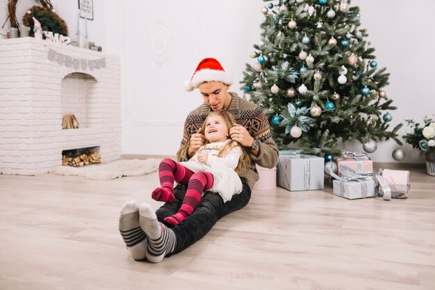 Generi con la figlia sulle gambe che celebrano il natale a casa