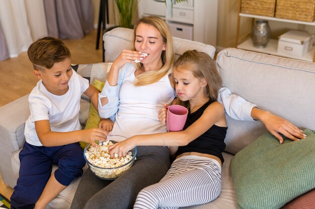 Generi ed i suoi bambini che mangiano l'alta vista del popcorn