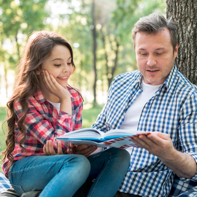 Generi il libro di lettura per sua figlia in parco