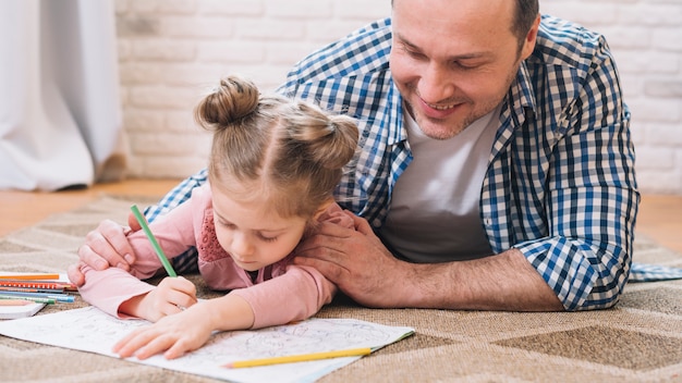 Generi la ragazza d&#39;assistenza nel disegno mentre si trovano sul tappeto a casa