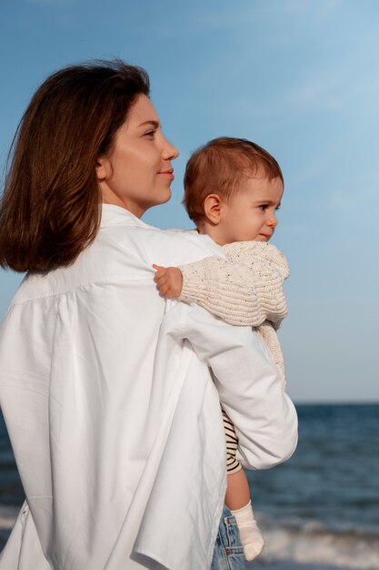 Genitore con un bambino sulla spiaggia al tramonto