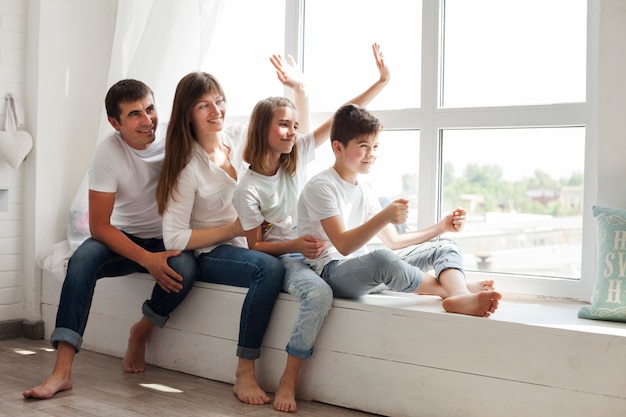 Genitore sorridente che gioca con l&#39;ubicazione dei loro bambini vicino alla finestra