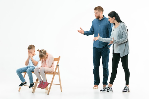 Genitori arrabbiati che rimproverano i loro figli - figlio e figlia a casa. Studio shot di famiglia emotiva. Emozioni umane, infanzia, problemi, conflitti, vita domestica, concetto di relazione