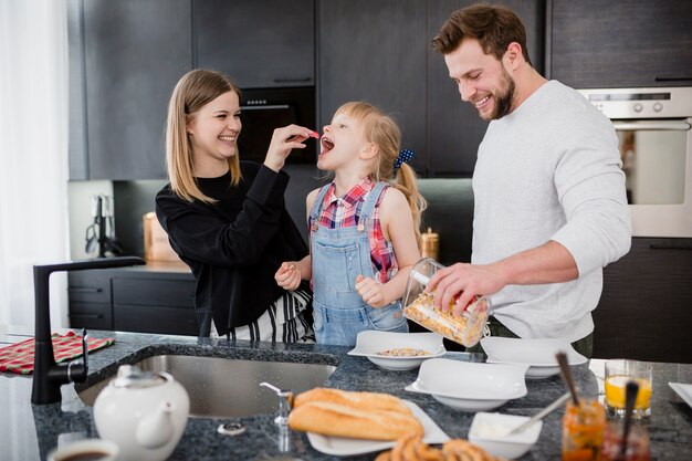 Genitori che alimentano figlia in cucina