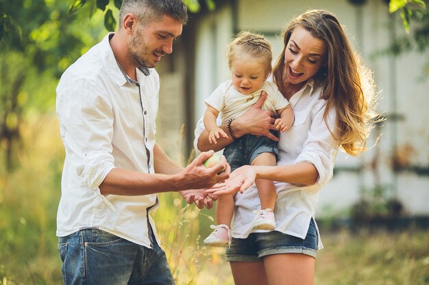 Genitori con bambino che godono di picnic in una fattoria con alberi di mele e ciliegi.