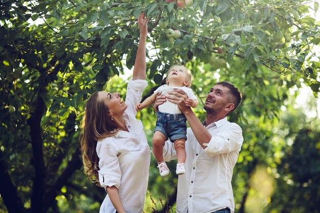 Genitori con bambino che si godono un picnic in una fattoria con mele e ciliegi.