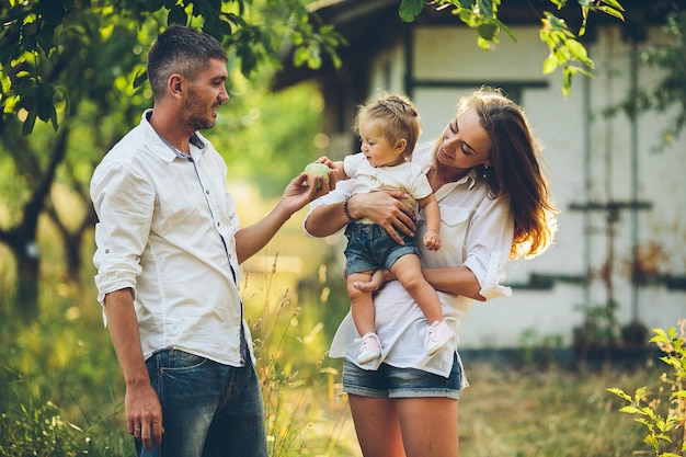 Genitori con bambino che si godono un picnic in una fattoria con mele e ciliegi.