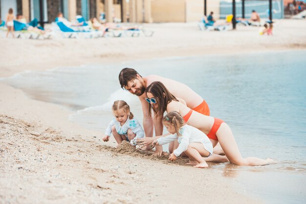 Genitori e bambini di vacanza di famiglia sul giorno di estate della riva di mare