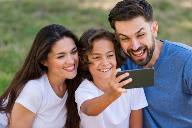 Genitori e bambino che prendono selfie insieme all'aperto