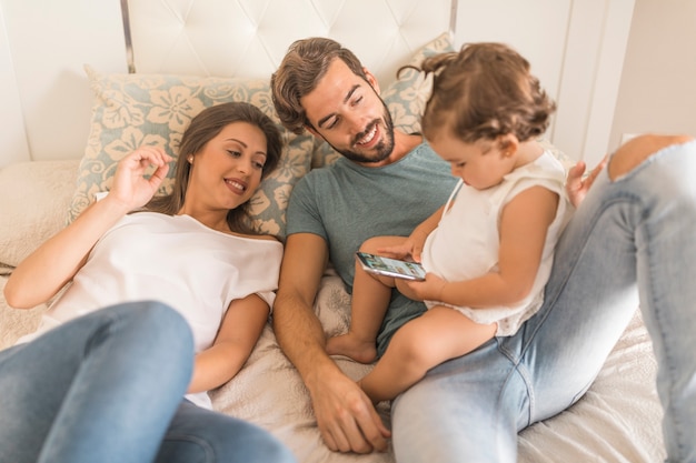 Genitori guardando figlia utilizzando smartphone